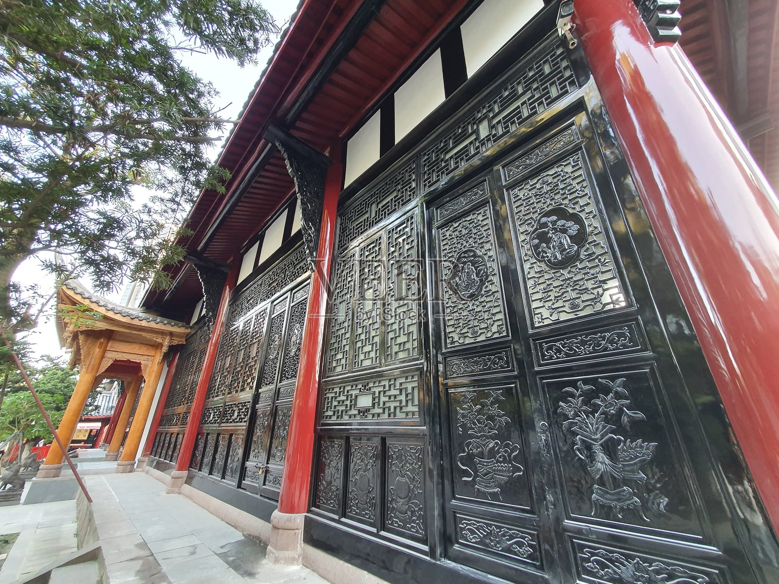 传统中国寺庙，精美的木雕，弯曲的屋顶，金色的书法匾额，映衬在晴朗的蓝天之下。照片摄影图片