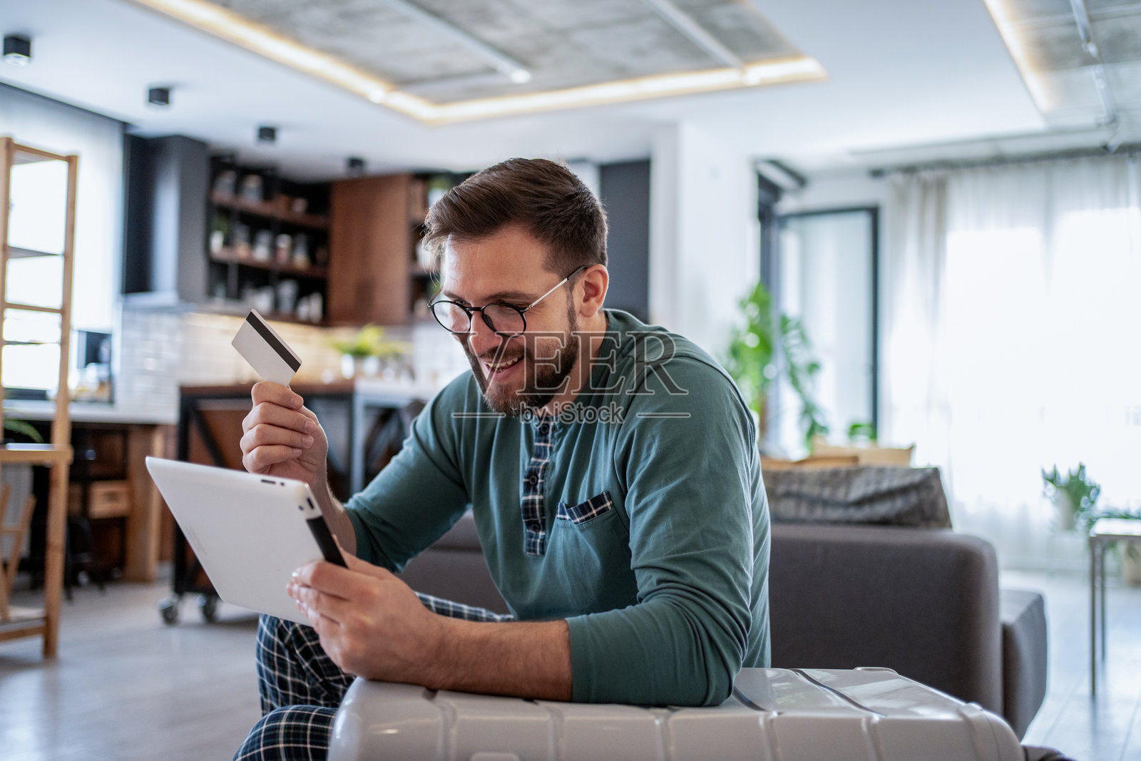 年轻男子使用平板电脑和信用卡在线预订旅行照片摄影图片