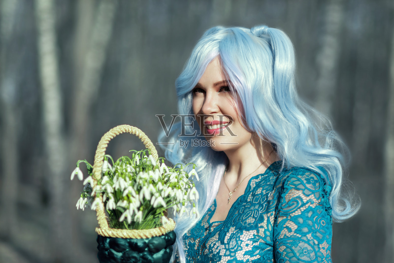 春天森林中一位美丽女孩的肖像，她有着长长的蓝色头发。魔法仙女穿着一袭蓝色华丽长裙，站在开满雪花莲的空地上。照片摄影图片