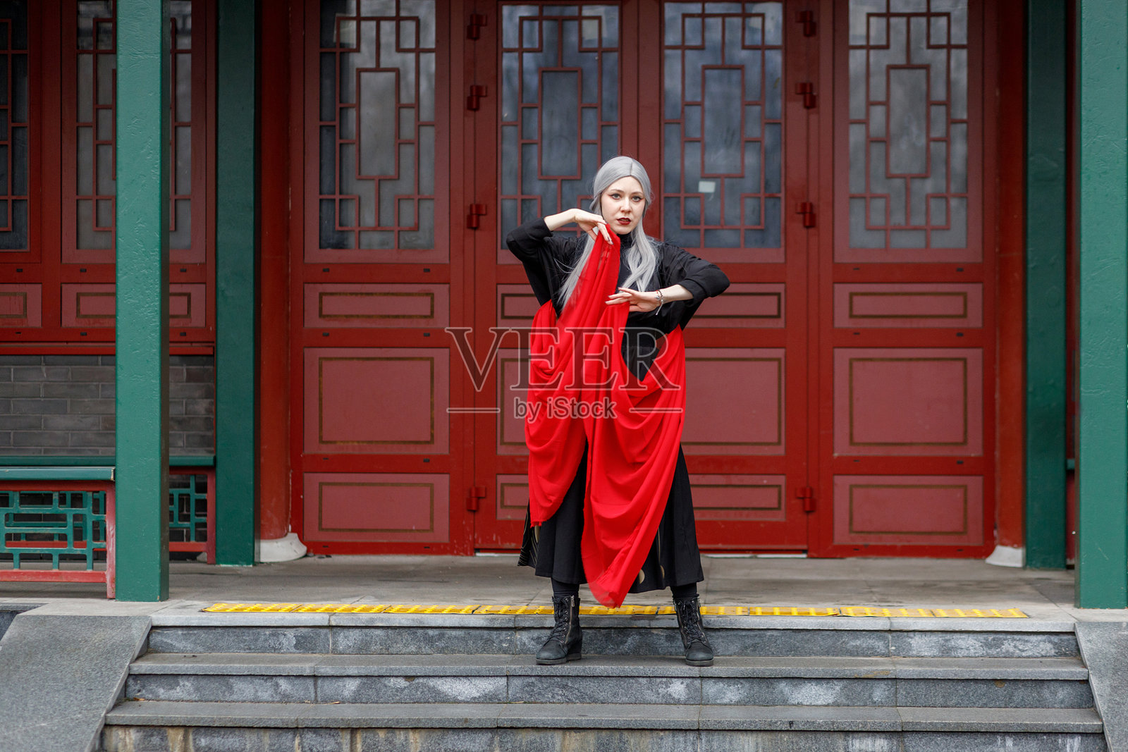 身穿中国传统服饰的女战士在舞动飞扬的红色布料，庆祝中国新年。照片摄影图片