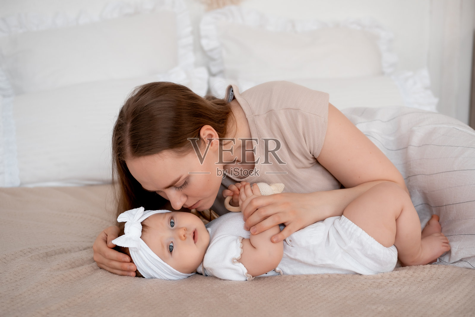妈妈和宝宝，母亲在床上陪玩并欣赏她的宝宝，母亲温柔地拥抱着宝宝，母爱与关怀。照片摄影图片
