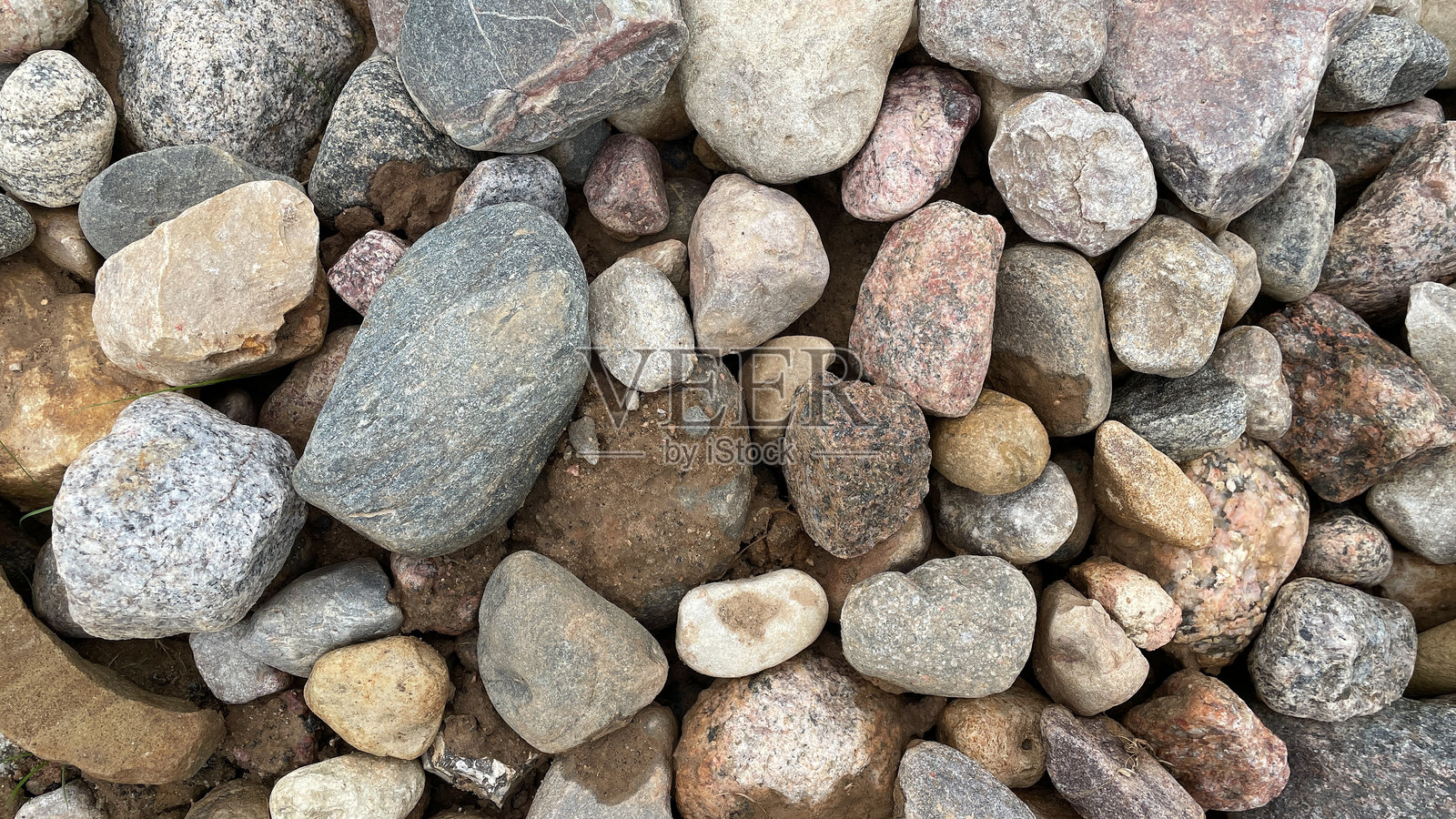 城市小径上的大大小小的石头特写，公园装饰，粉色和灰色的卵石照片摄影图片