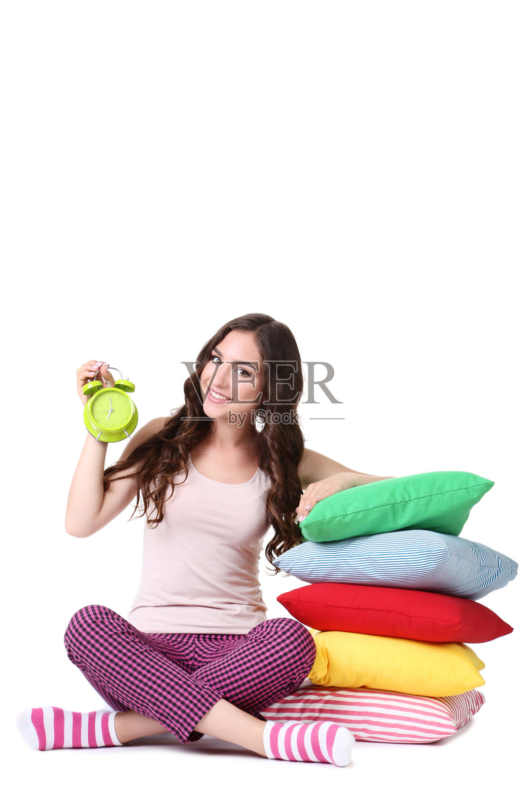 美丽的女孩与闹钟和五彩缤纷的枕头在白色背景上照片摄影图片