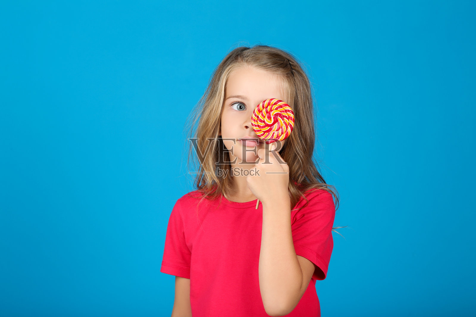 蓝色背景下手持棒棒糖的小女孩照片摄影图片