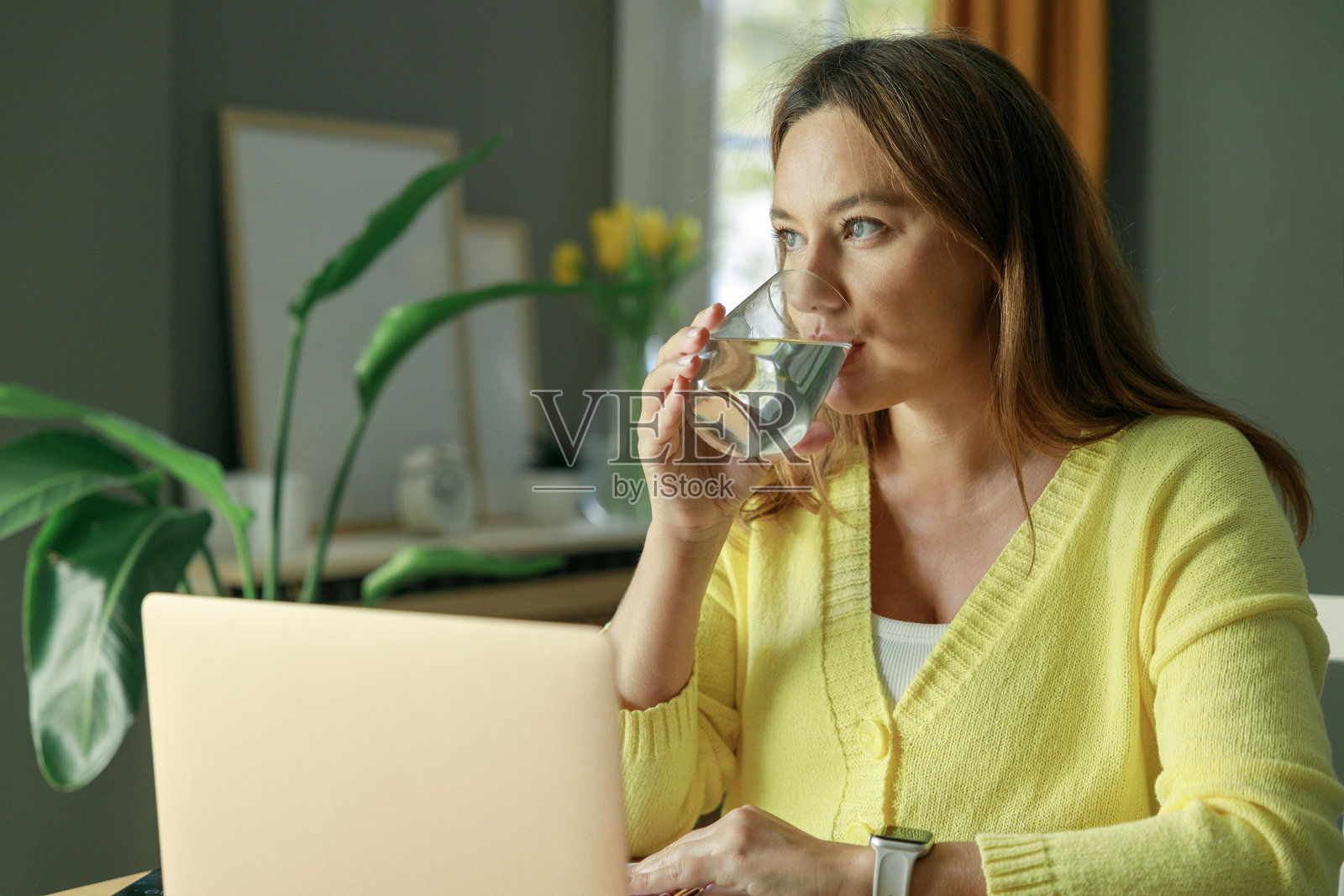 年轻女性在家工作并喝水照片摄影图片