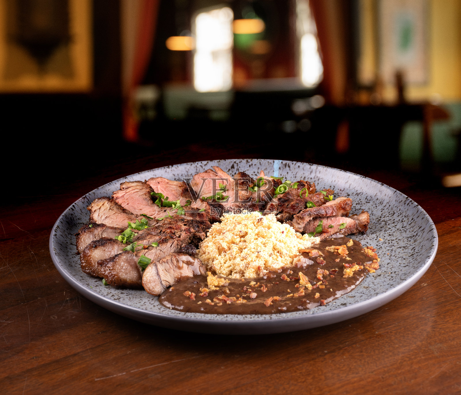 切成条的西冷牛排，配以法罗法和红酒酱，背景模糊的酒吧。照片摄影图片