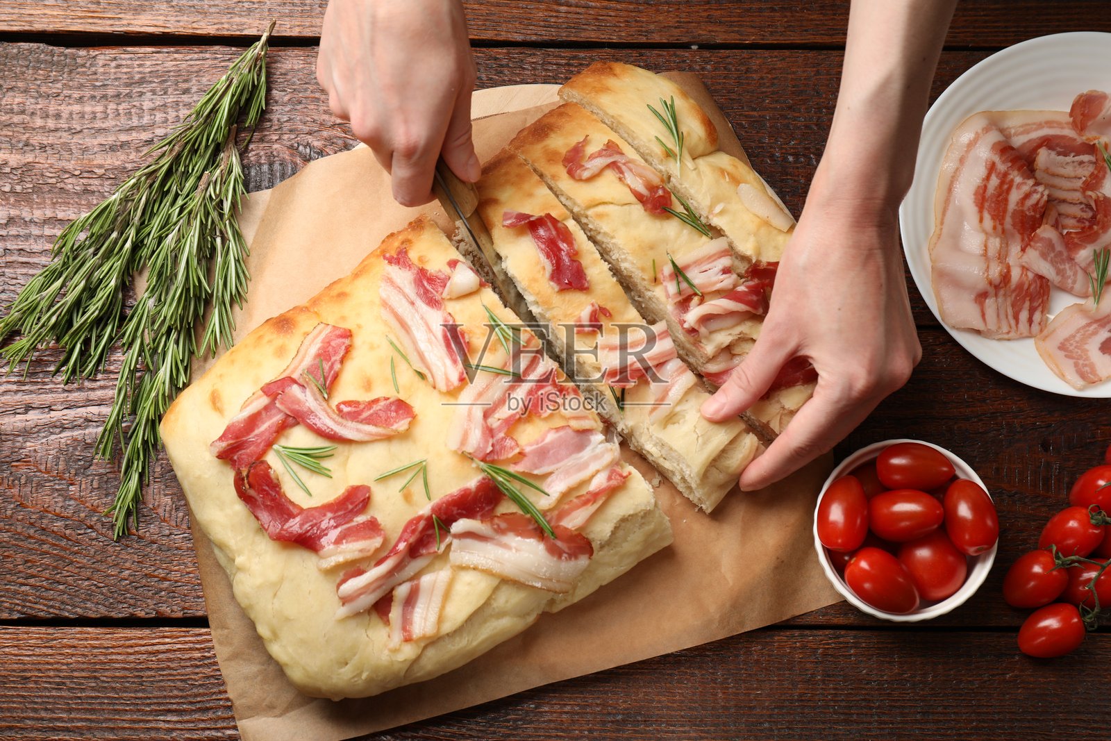 女人在木桌上切割美味的佛卡夏面包，俯视图照片摄影图片