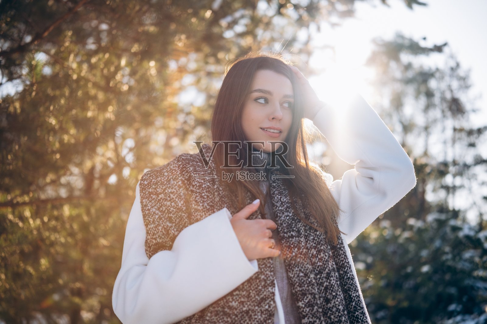 冬日散步时，年轻女性在松树间的肖像。照片摄影图片