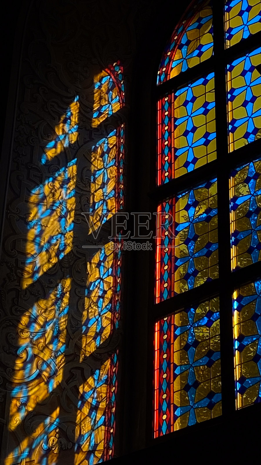 蓝色和黄色图案的彩色玻璃窗投射出阴影照片摄影图片