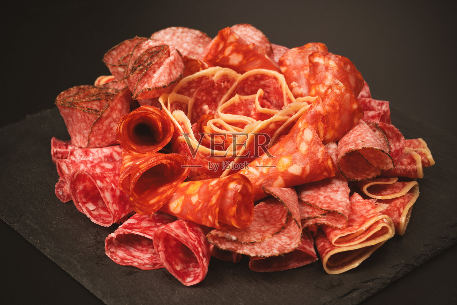 不同种类的肉切块放在砧板上。照片摄影图片