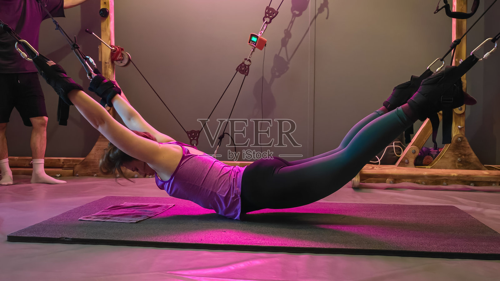 年轻女性在健身房使用悬挂训练器进行背部伸展练习照片摄影图片