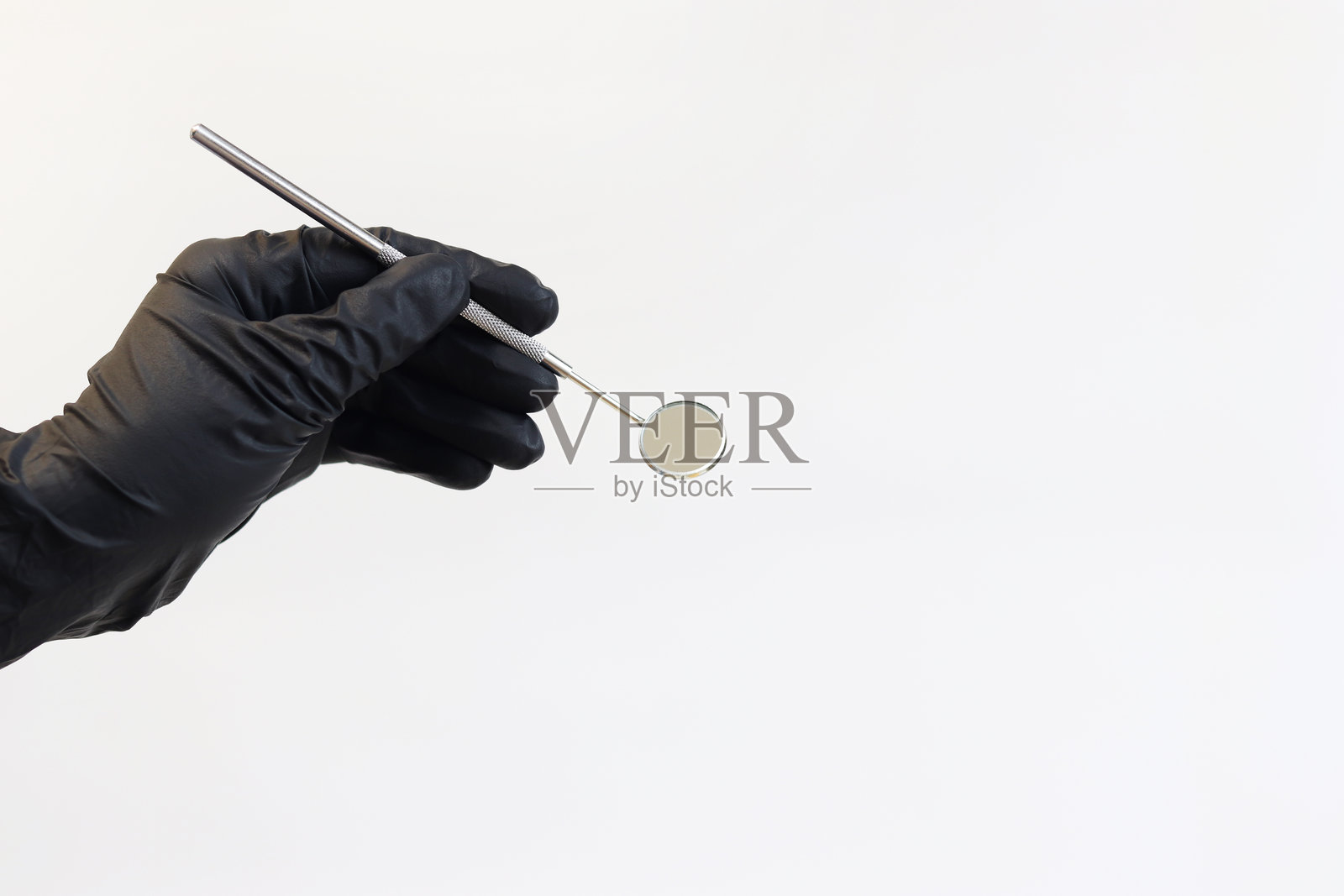 戴着黑色医疗手套的手握着牙科镜照片摄影图片