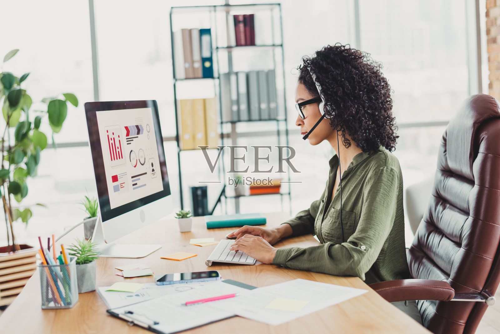 现代办公室中的职业女性正在使用电脑分析数据，展示了专业的工作空间和企业服装。照片摄影图片