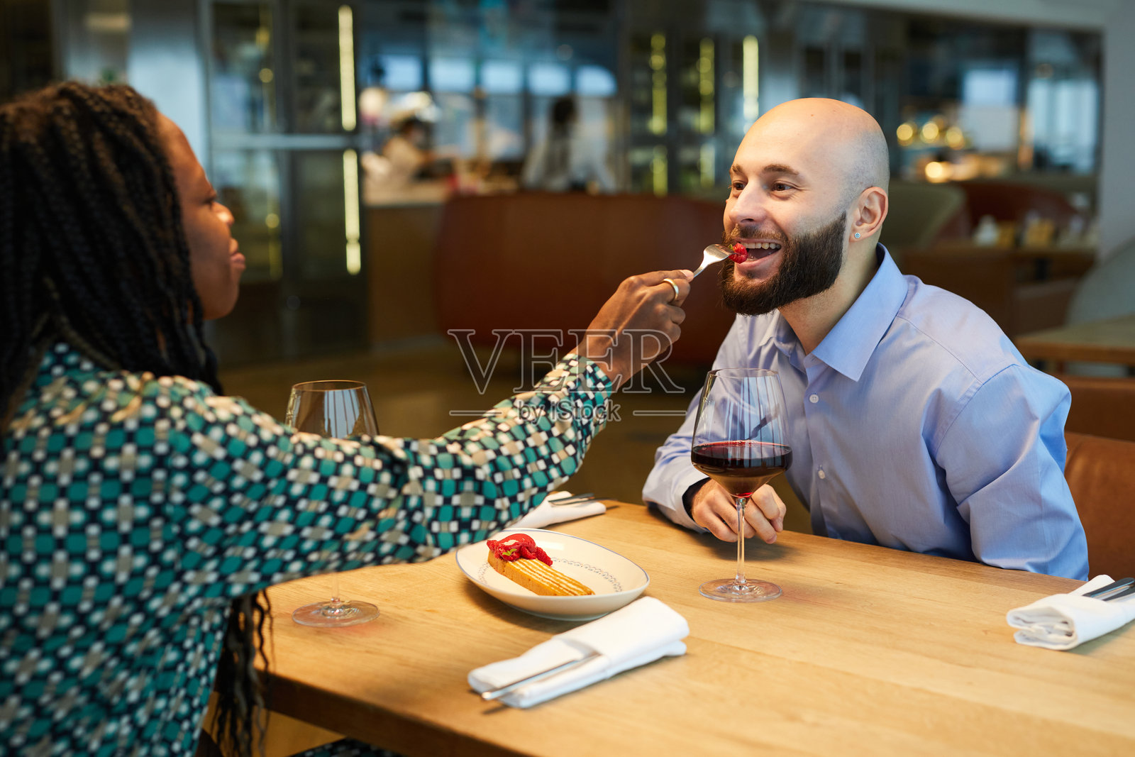 女人在餐厅喂她的男朋友照片摄影图片