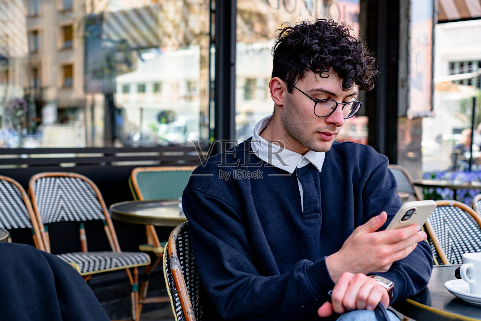 年轻男子在巴黎的户外咖啡馆使用智能手机照片摄影图片
