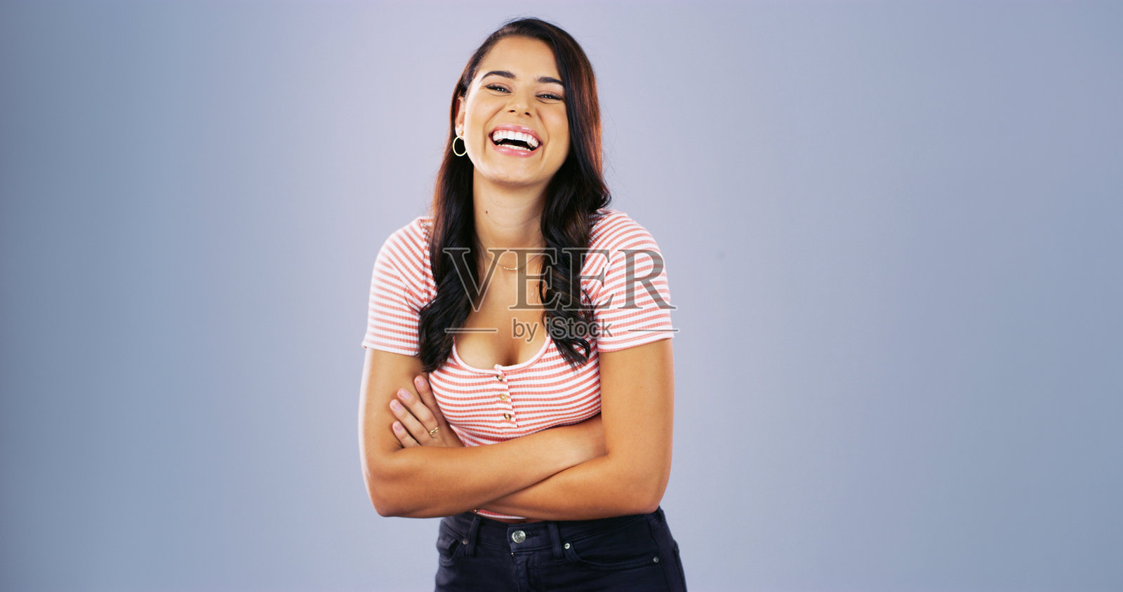 笑着的学生，双臂交叉，背景是一位女性的肖像，适合大学奖学金的拍摄，幽默或样板空间。快乐、教育和大学，背景中有年轻人、漫画和学术元素。照片摄影图片