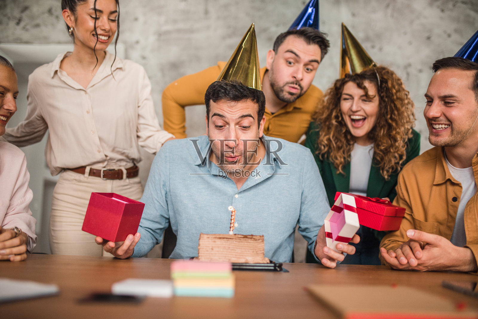 商务人士吹灭同事为他准备的生日蛋糕上的蜡烛照片摄影图片