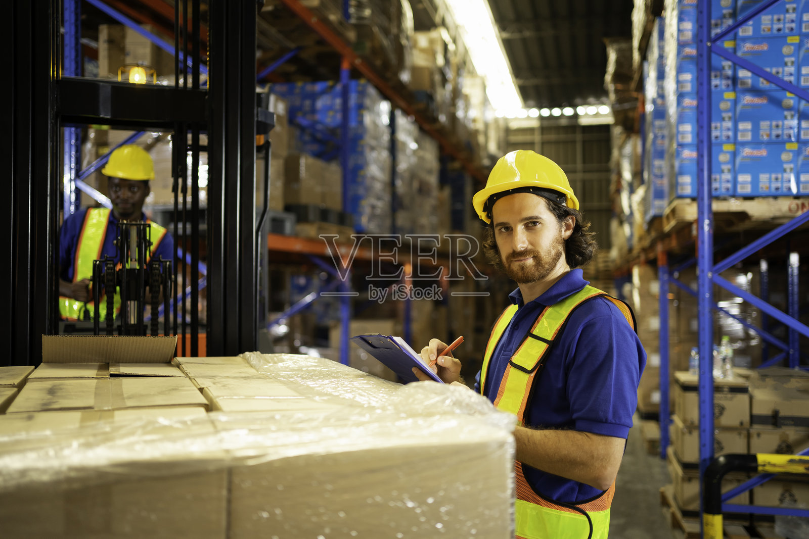 仓库工人在配送中心检查库存，展示安全装备和高效的组织。照片摄影图片