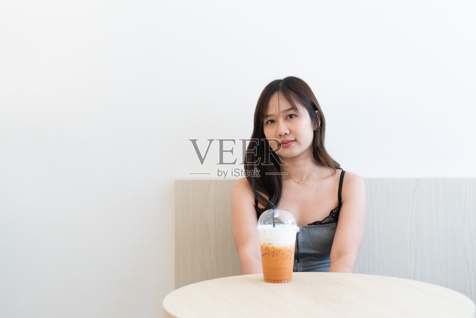 美丽的亚洲女性在咖啡店喝泰式奶茶照片摄影图片