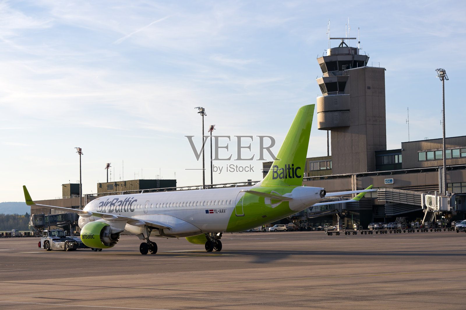 低角度视图的巴尔特航空空客A220-300（注册号YL-AAV）在春季日落时离开瑞士苏黎世克洛滕机场。照片摄影图片