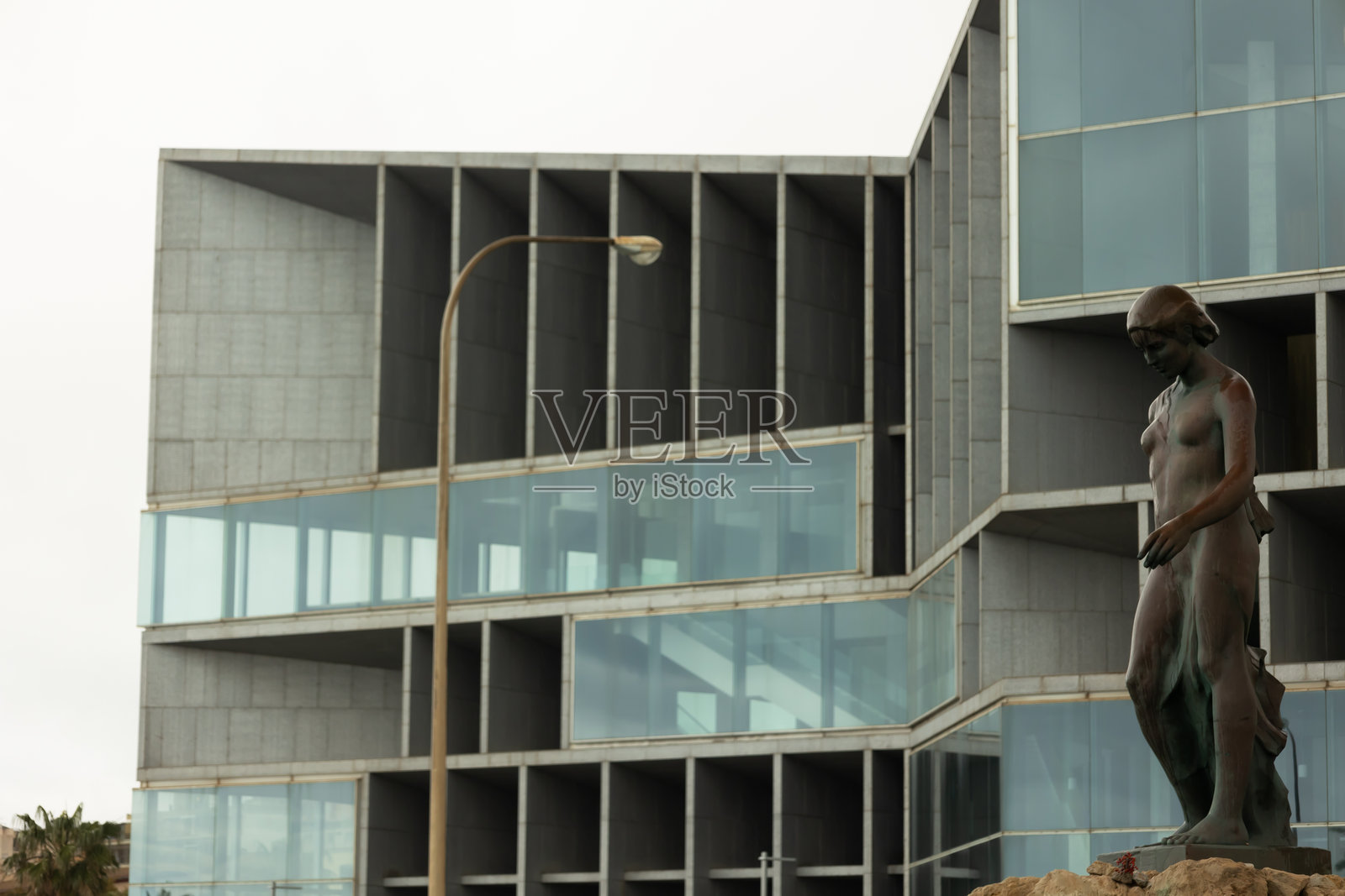 努雷杜纳雕像,马洛卡诗人米格尔·科斯塔·伊·略贝拉创作的神话人物,背景是现代基础设施照片摄影图片