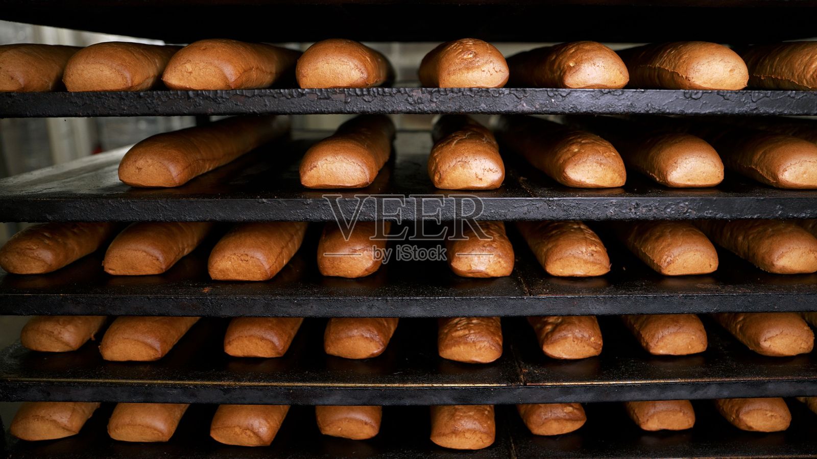 新鲜出炉的面包在面包店的金属架上冷却照片摄影图片