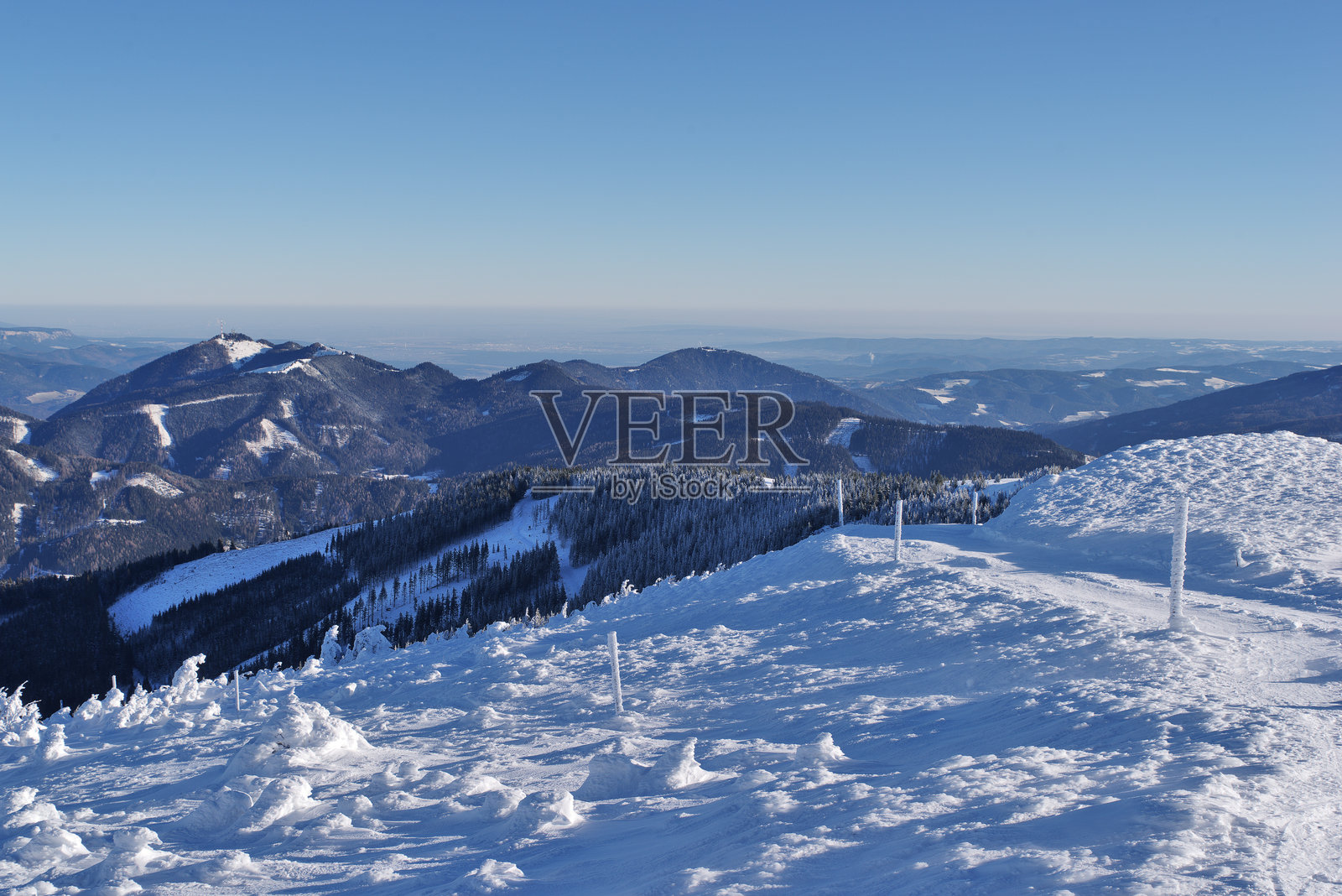 蓝天映衬着被雪和霜覆盖的冬季风景，远景。奥地利施蒂利亚州的斯图赫尔克，背景中可见索恩温德斯坦山。照片摄影图片