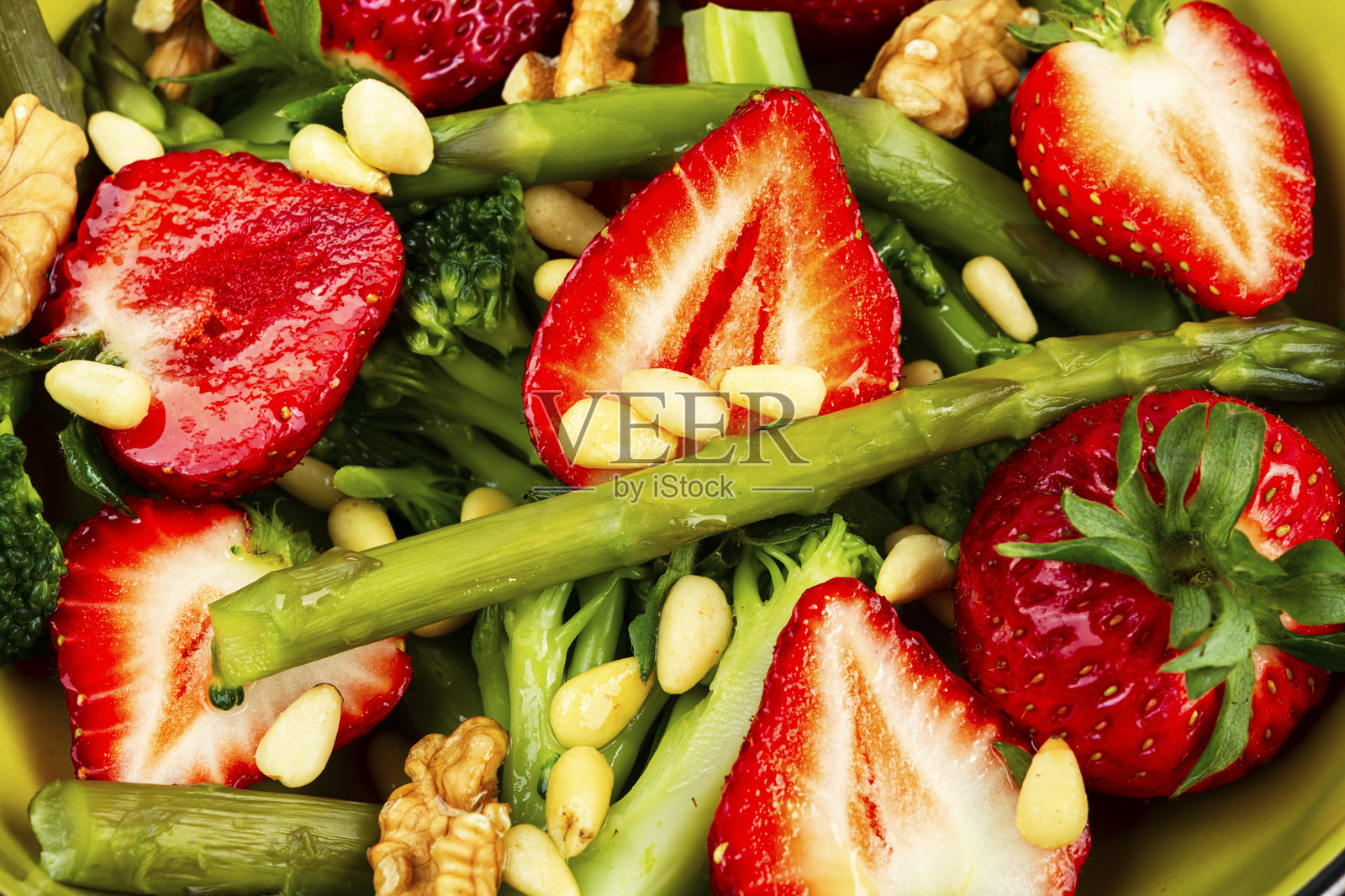 绿色混合沙拉，配有绿色芦笋和草莓。照片摄影图片