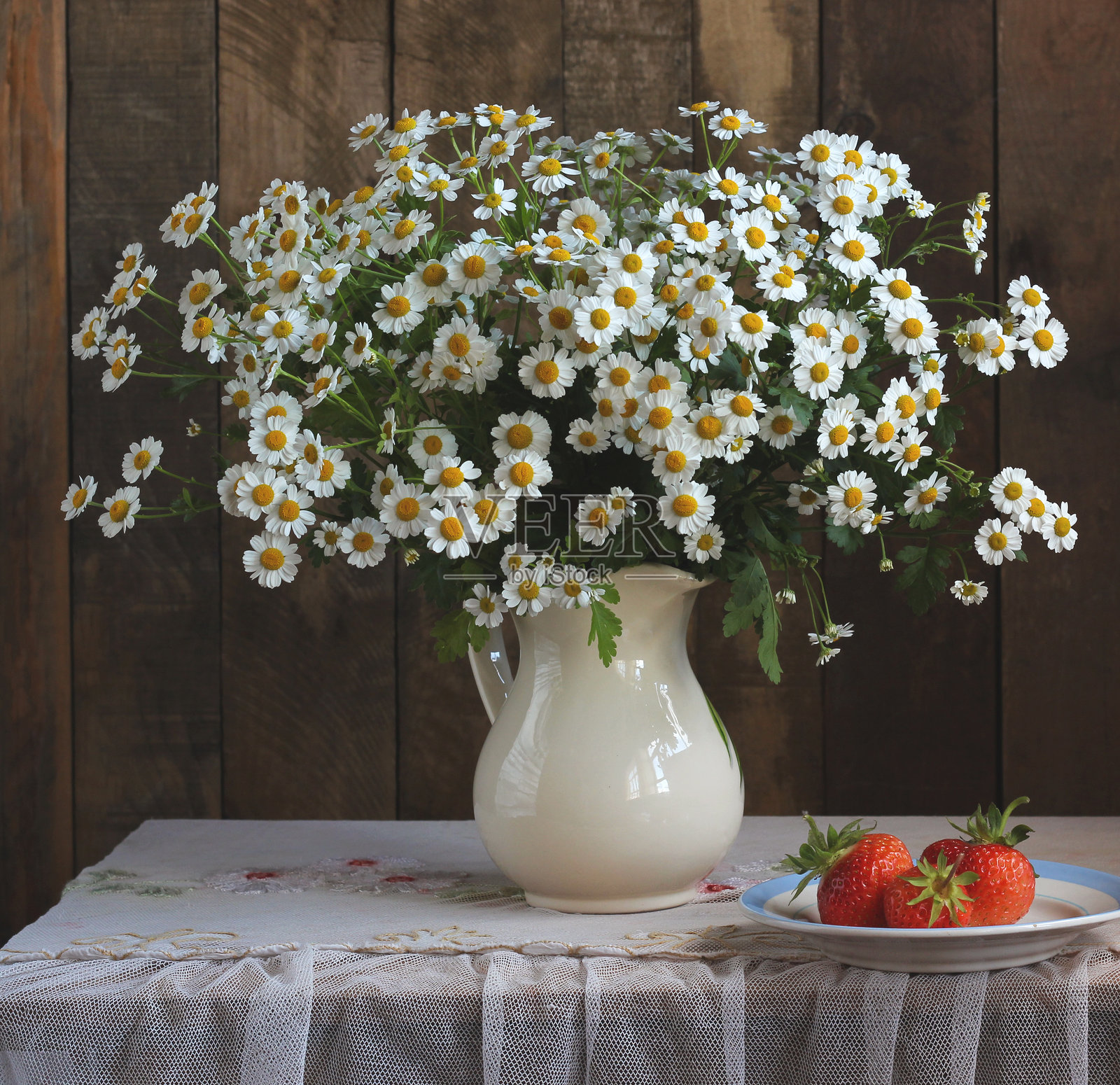 白色水壶中的千里香花束与桌上的草莓照片摄影图片