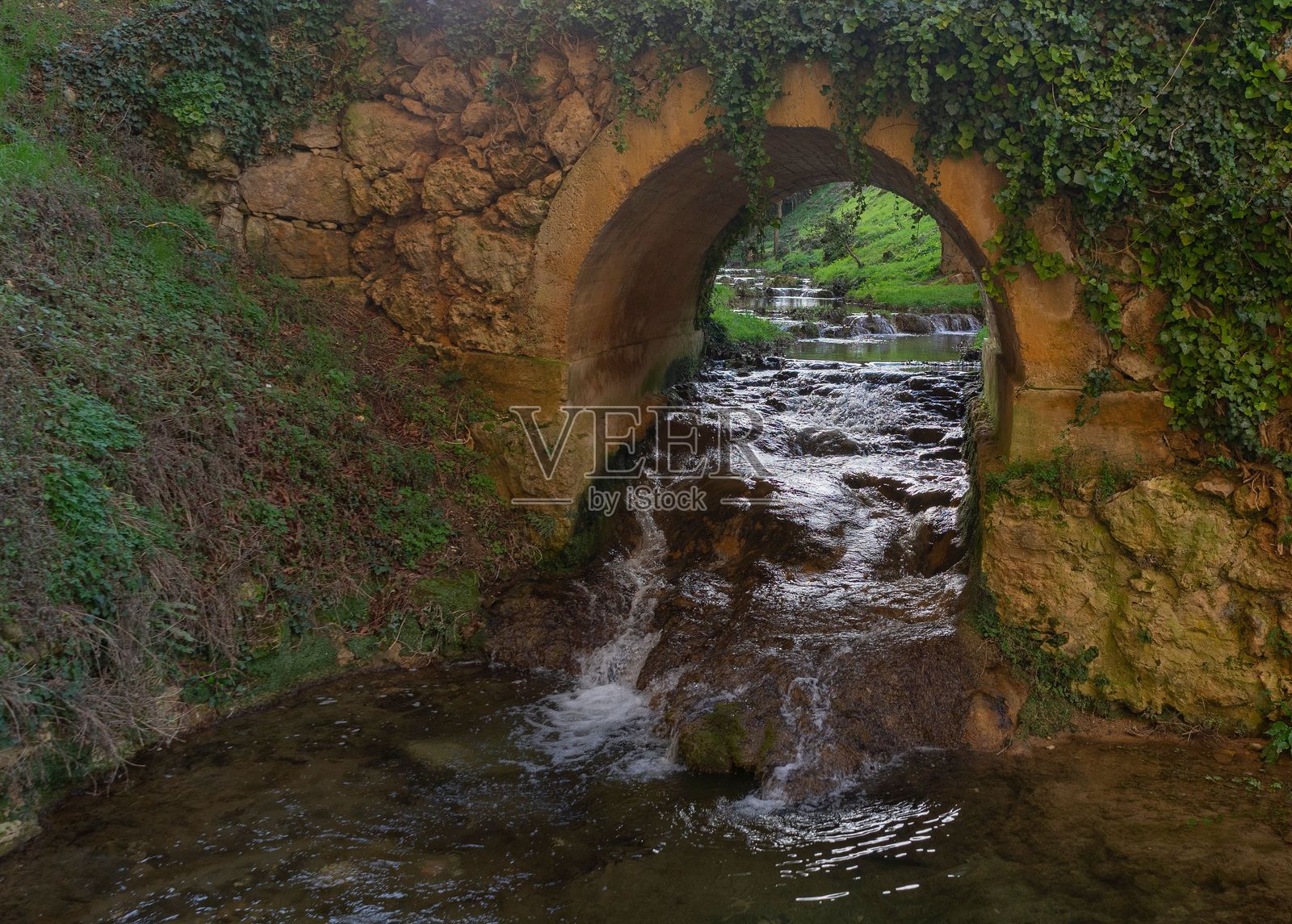 石拱桥横跨流动的小溪。照片摄影图片