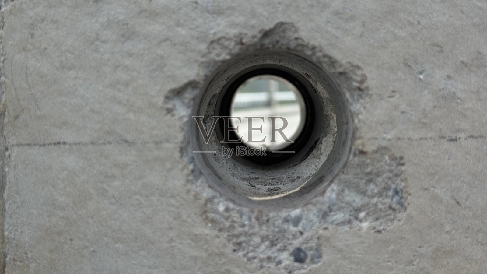 灰色混凝土墙上的圆形开口特写，展示了纹理、细节和建筑元素。照片摄影图片