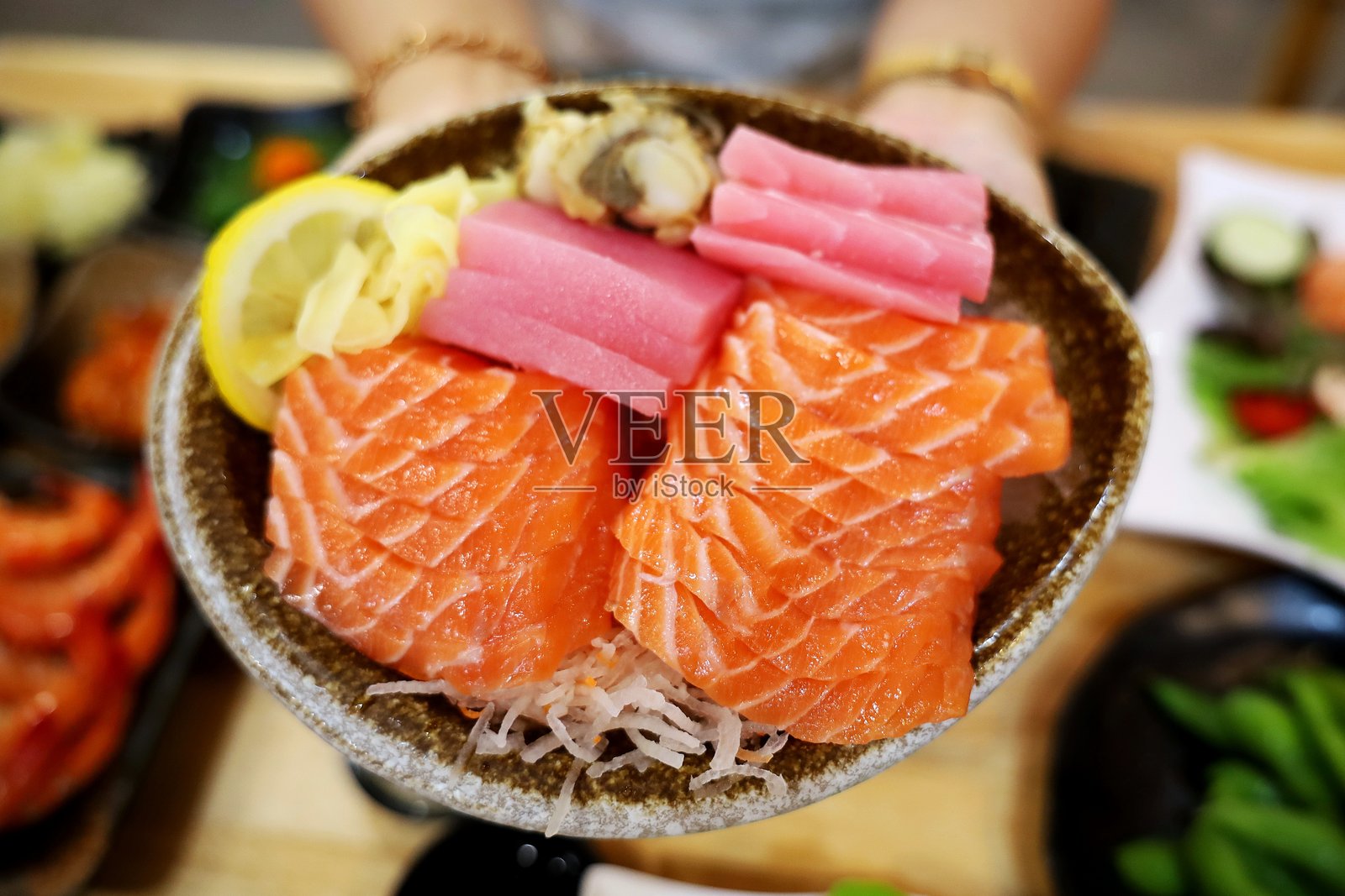 手握三文鱼和金枪鱼刺身碗 - 日本料理。照片摄影图片