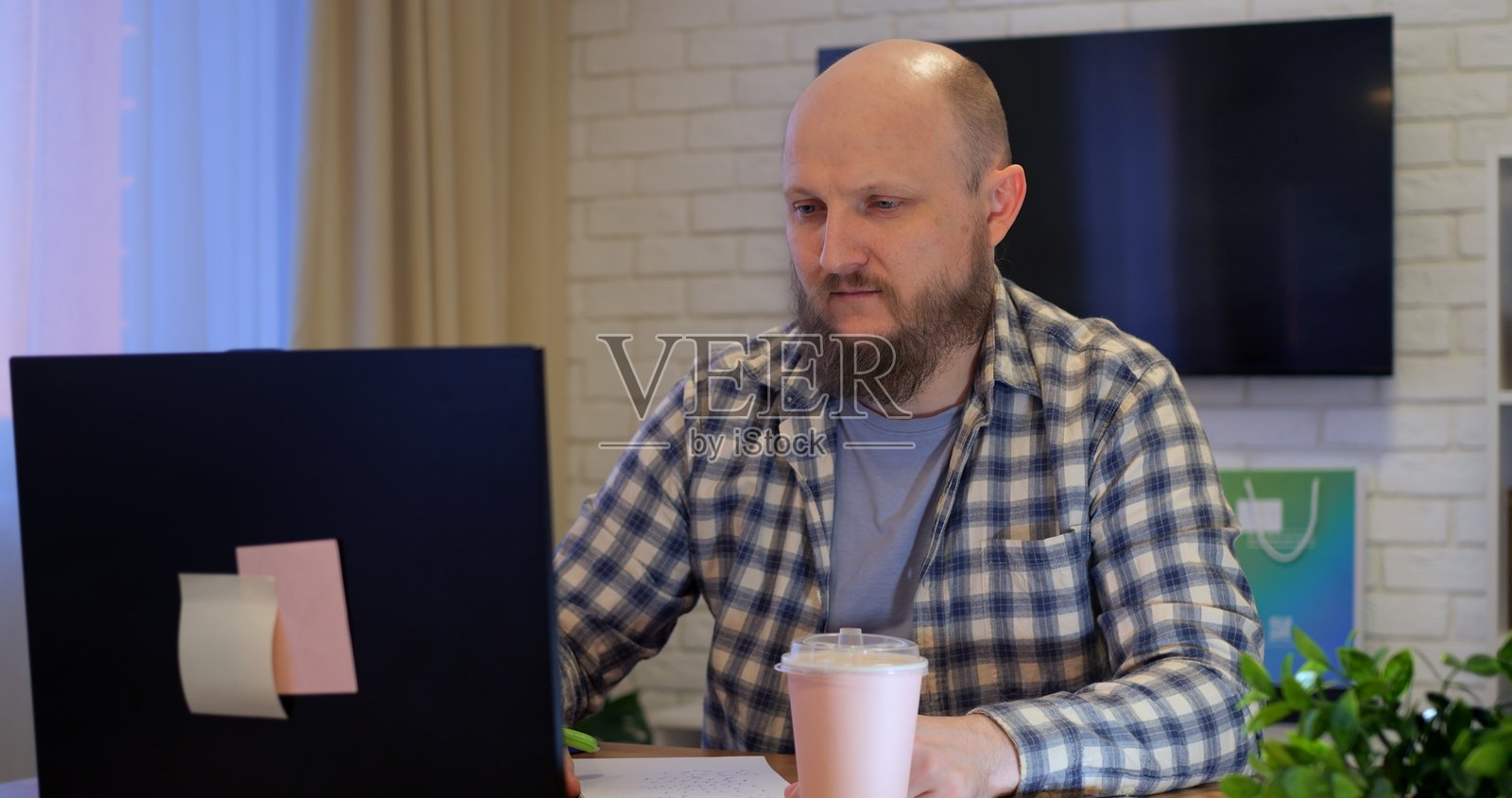 秃头男子在家中的餐桌上打开笔记本电脑开始工作，处于隔离期间。在隔离或假期期间居家办公。工作狂在休息日从家中工作。照片摄影图片