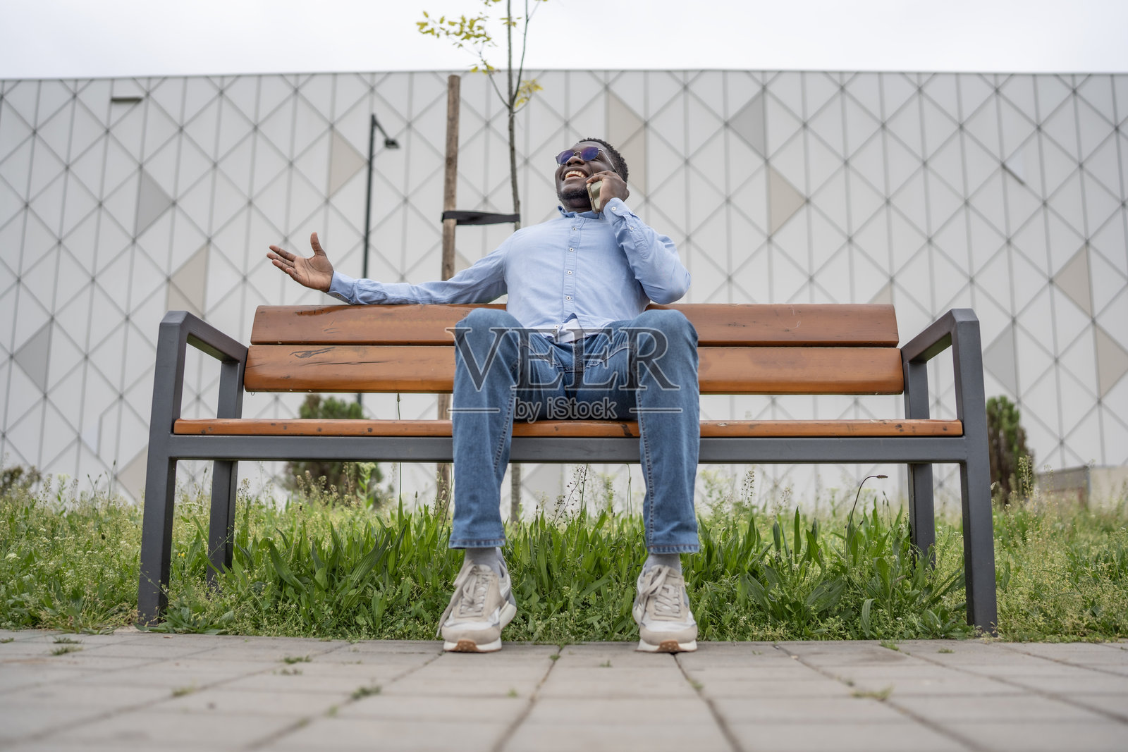 坐在长椅上的男人愉快地用智能手机聊天照片摄影图片