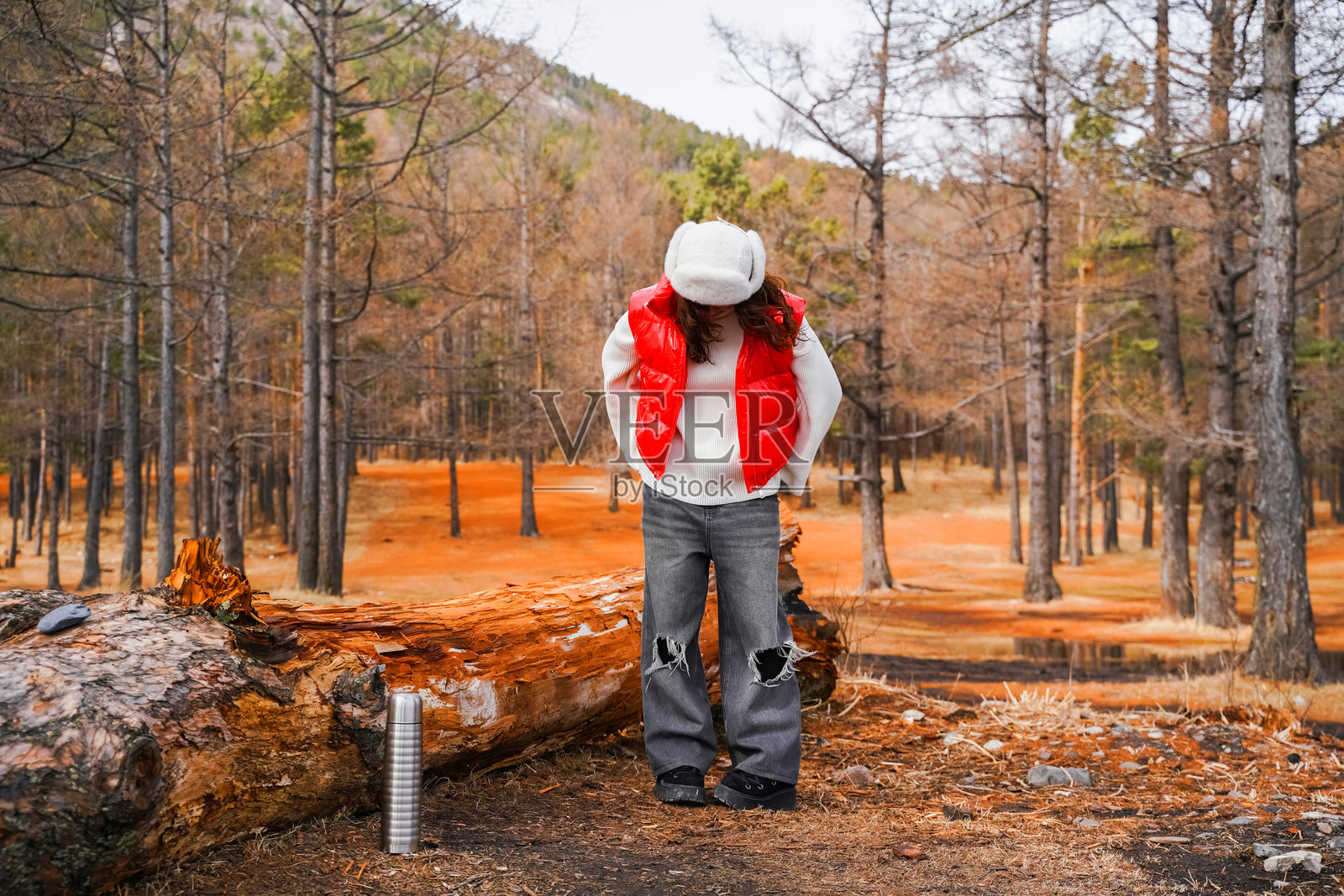 年轻女性与美丽的山谷在秋天的多彩日落中。十几岁的女孩，橙色的草地和秋天的树木。徒步旅行。照片摄影图片
