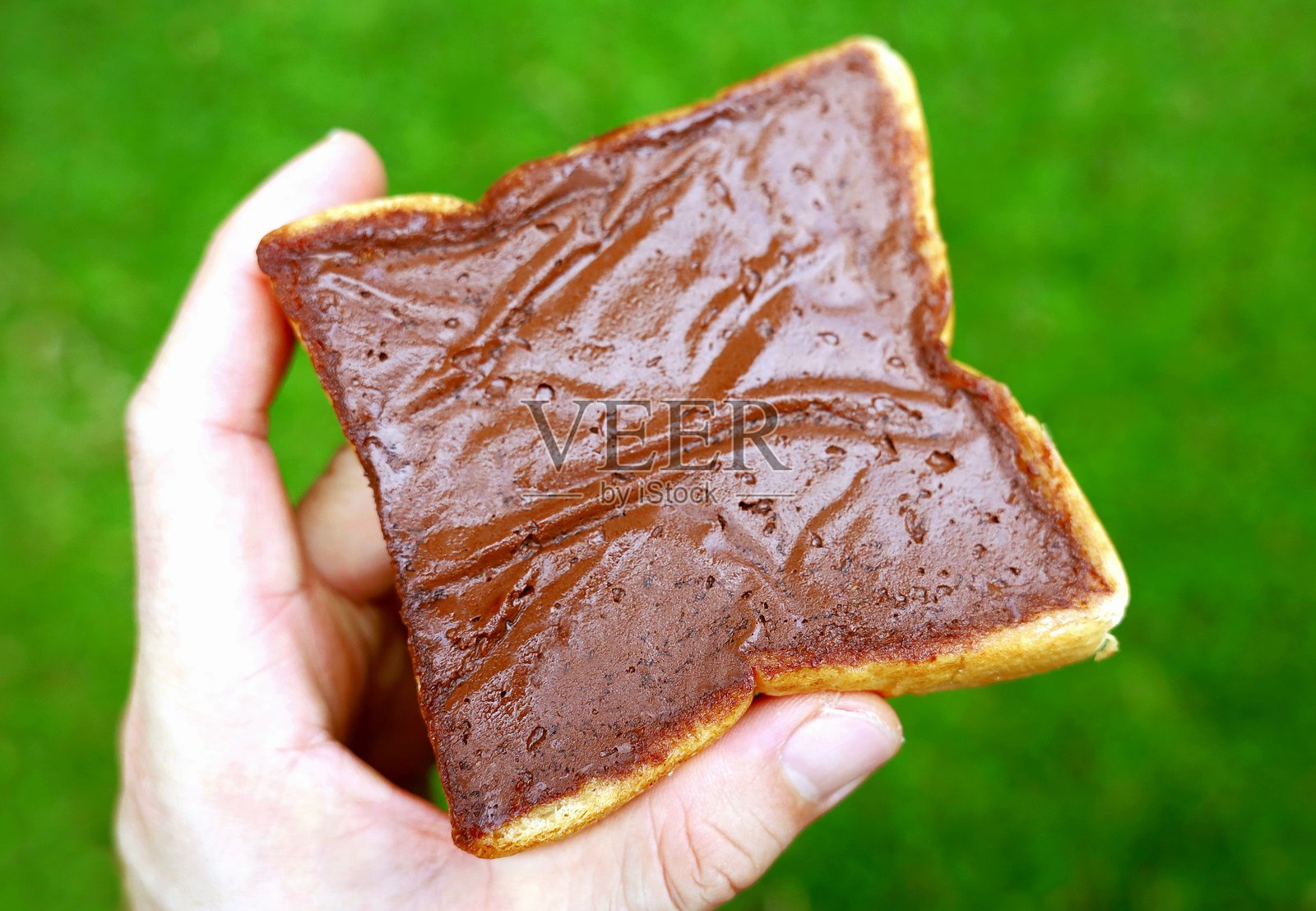 在面包片上涂抹巧克力酱。照片摄影图片