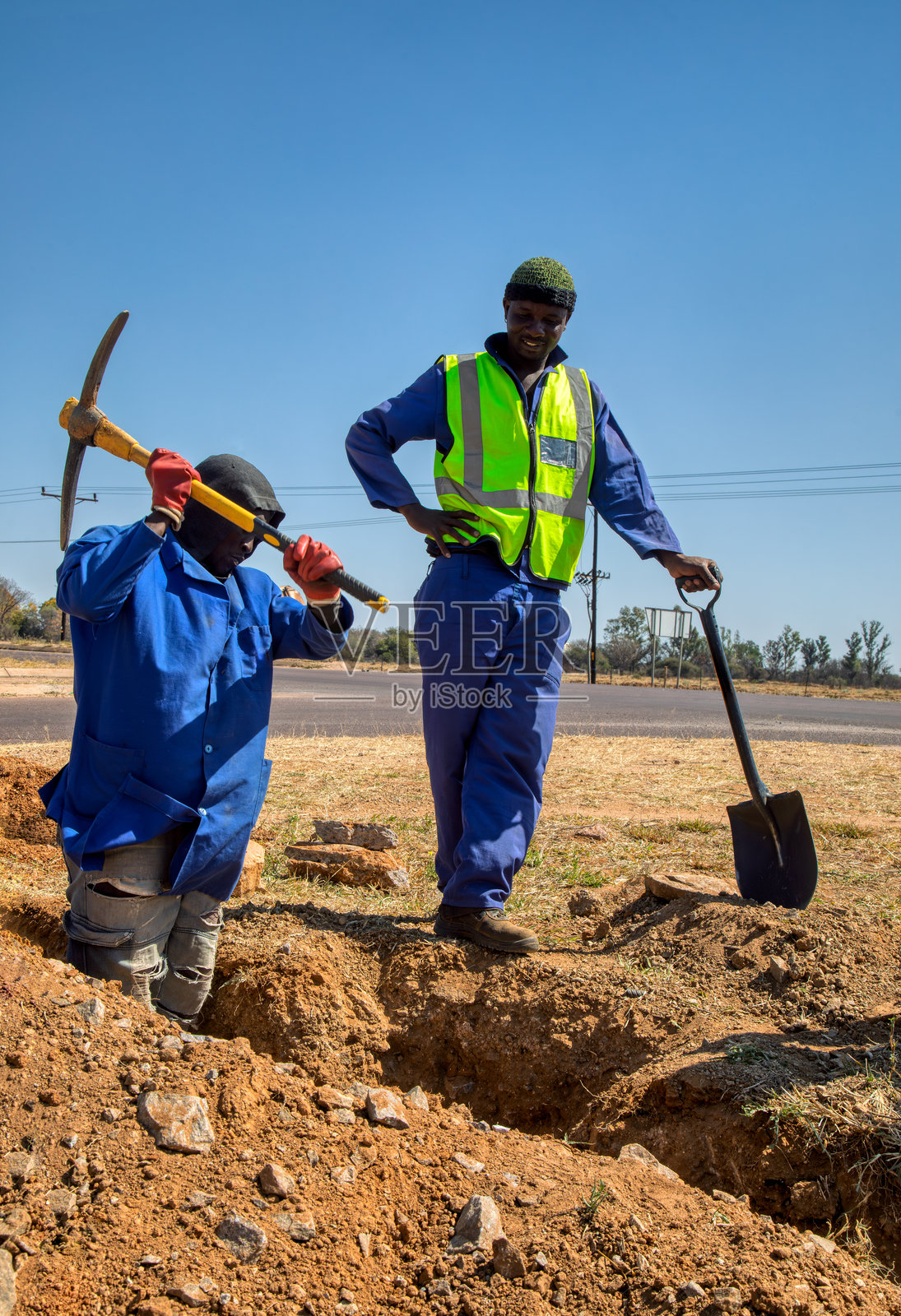 非洲工人在挖掘道路，进行水管维修和基础设施建设，使用铲子和镐，展示他们的工作。照片摄影图片