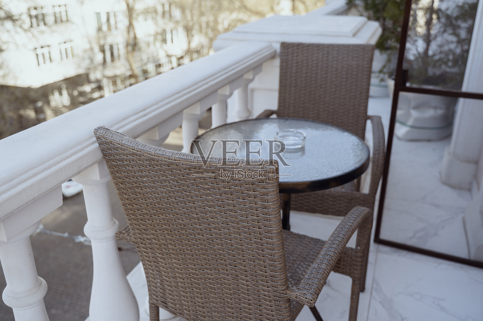酒店或房子的阳台上有一张桌子，两把椅子，桌子上有一个烟灰缸。照片摄影图片