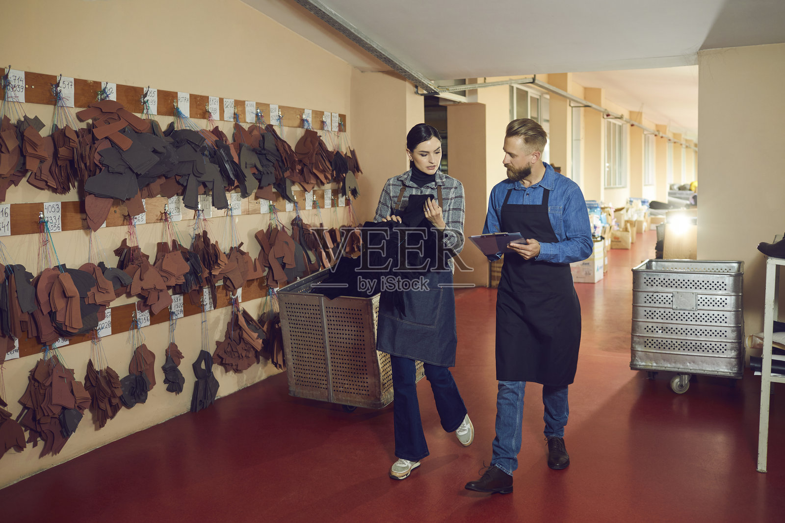 两名专门从事鞋子和服装缝制的工厂员工讨论新设计。照片摄影图片