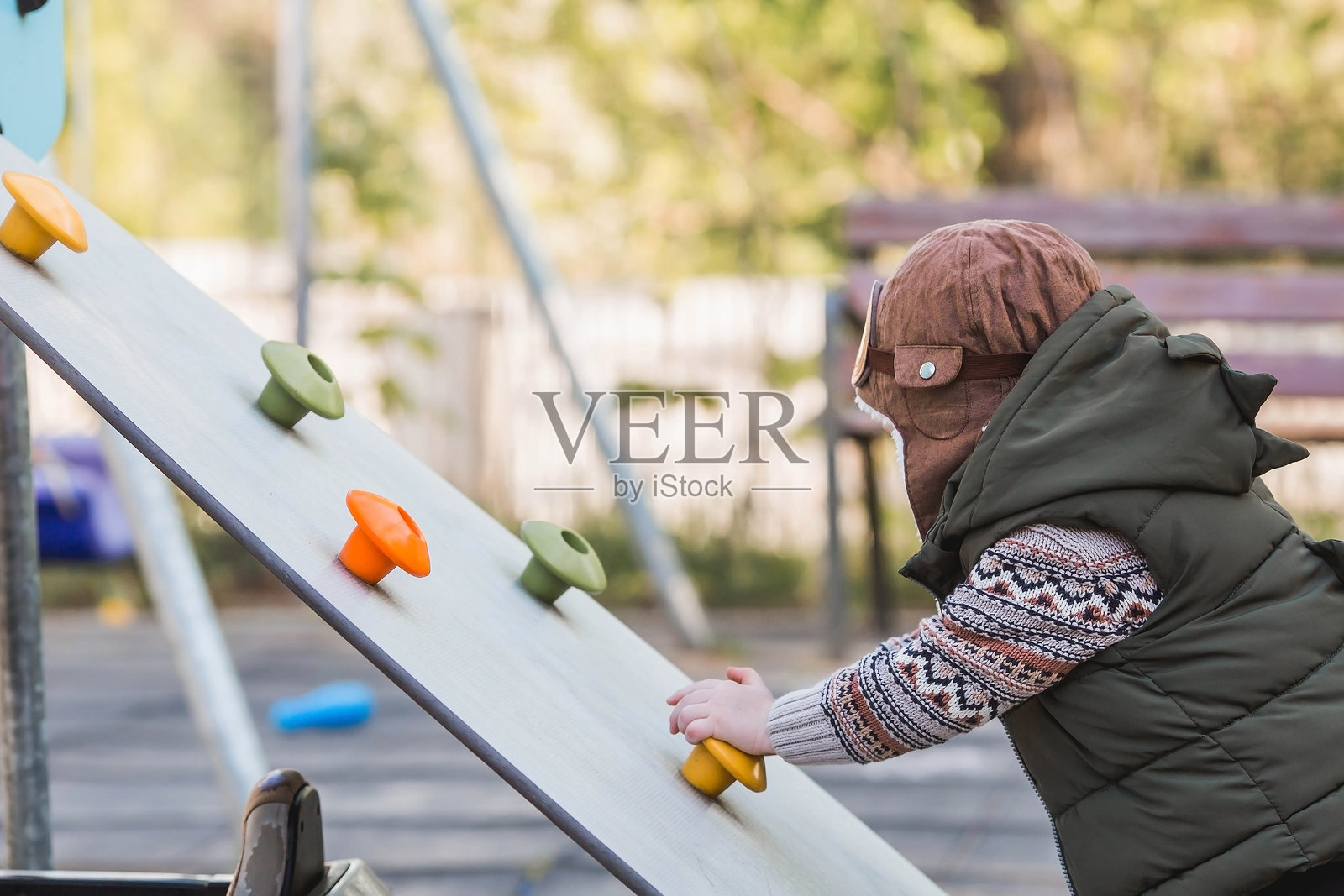 童年。一个小男孩正在游乐场玩耍。攀爬架上爬山。美丽的孩子在户外玩耍的肖像。照片摄影图片