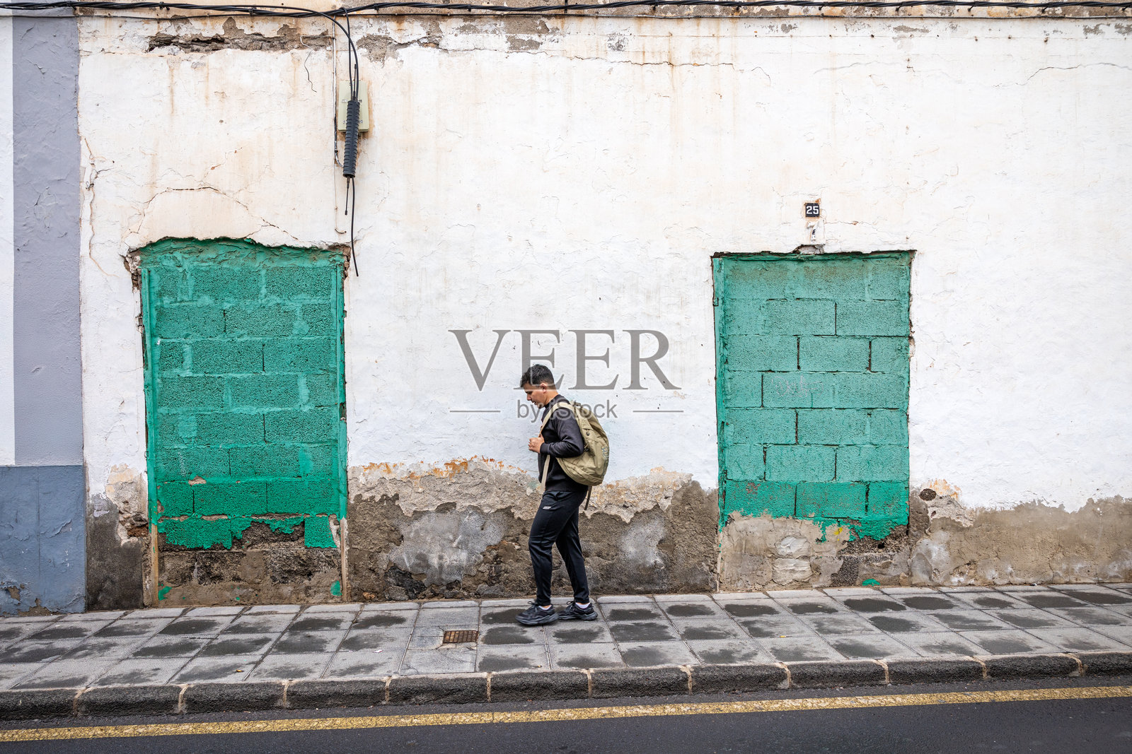 年轻男子在城市环境中走过封闭的砖砌门口照片摄影图片