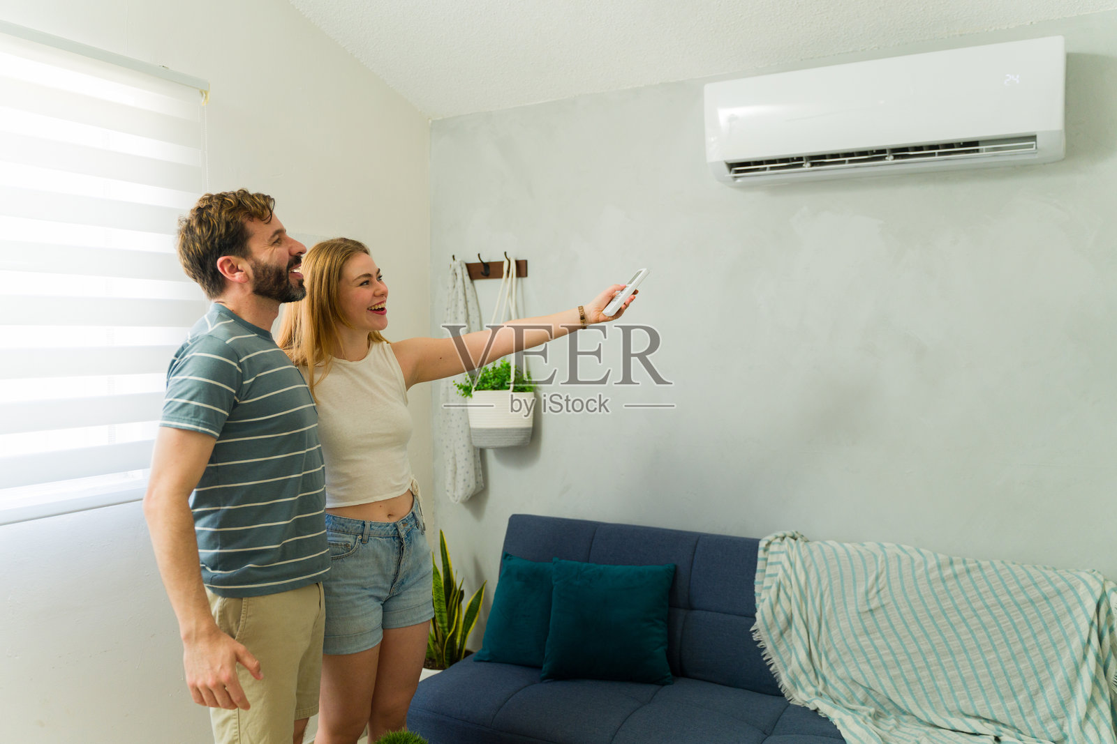快乐的情侣在夏天的家中打开空调机照片摄影图片