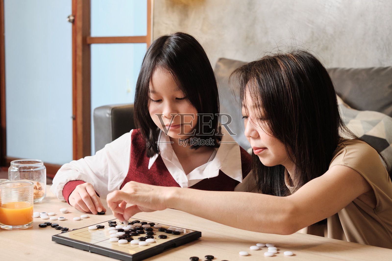 亚洲妈妈和孩子在客厅的桌子上玩跳棋。照片摄影图片