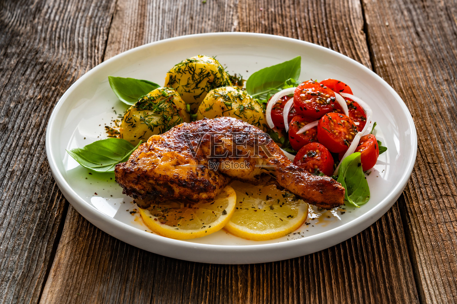 木桌上的烤鸡腿配煮土豆和新鲜蔬菜沙拉照片摄影图片
