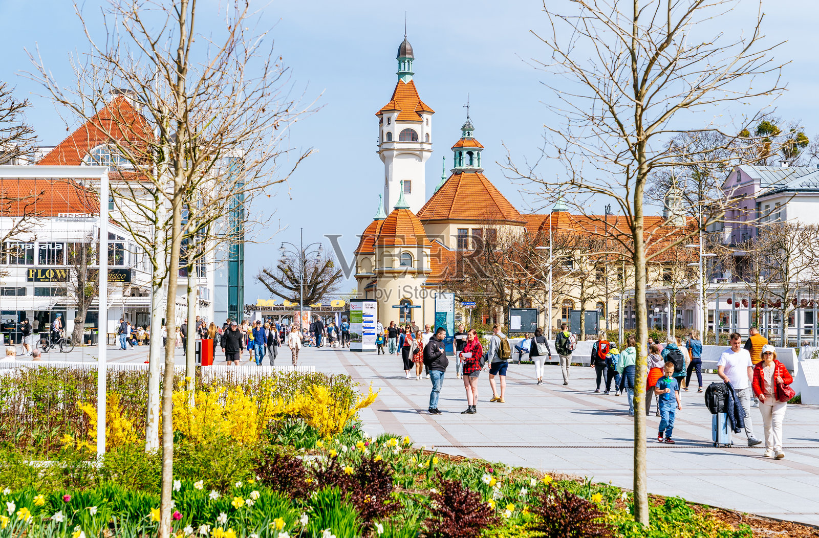 色彩斑斓的花坛和绿化带在索波特友谊广场，清晰的日子里，人们朝着温泉大厦和灯塔走去。照片摄影图片