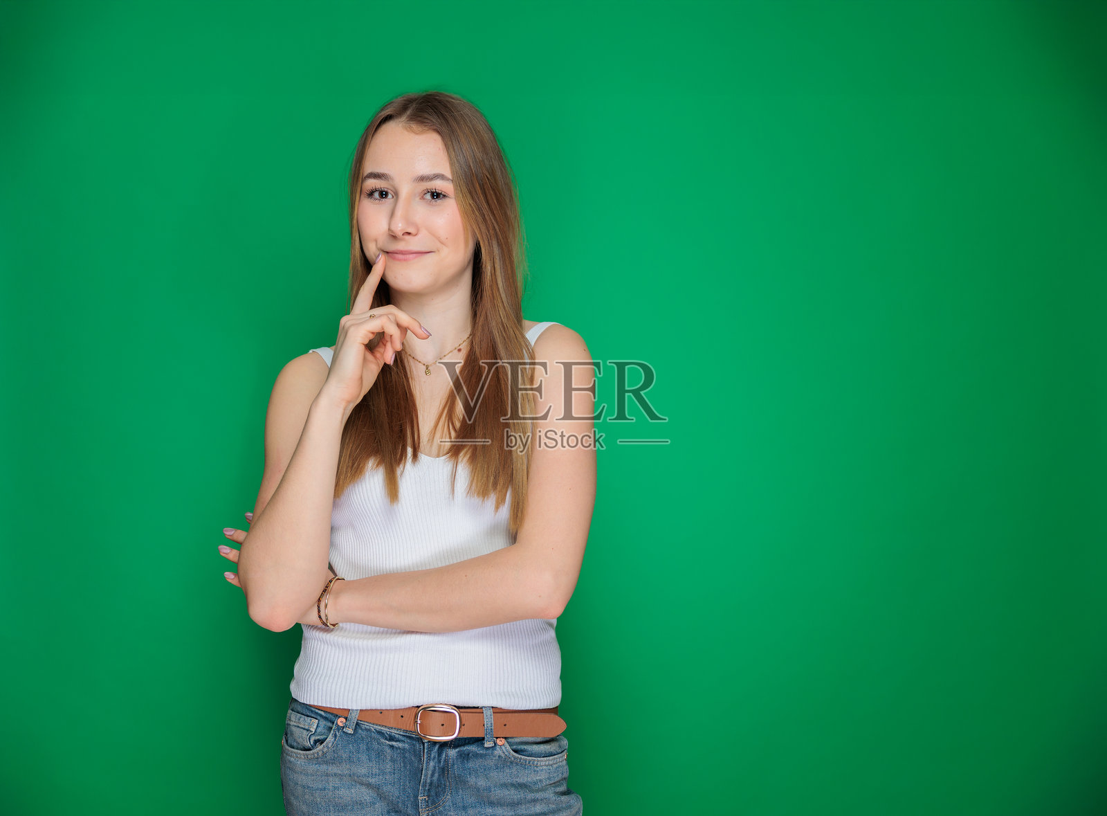 微笑的年轻女性，手托下巴，背景为绿色照片摄影图片