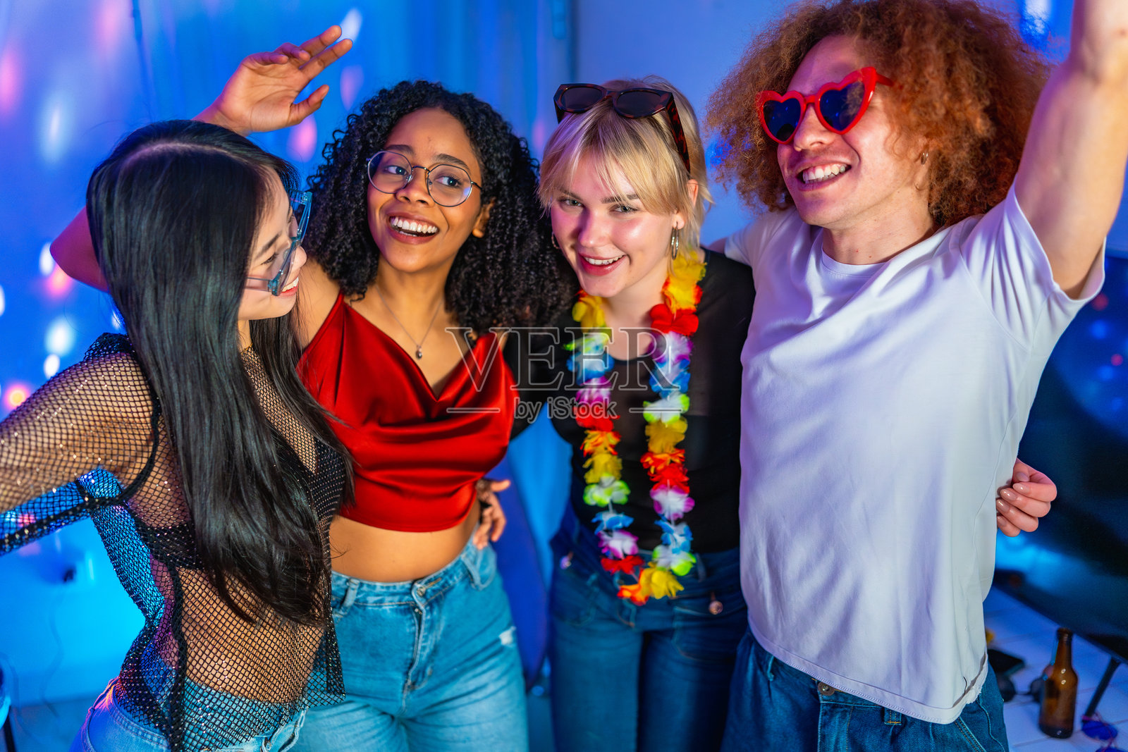 年轻人们在五光十色的灯光下一起享受派对。照片摄影图片