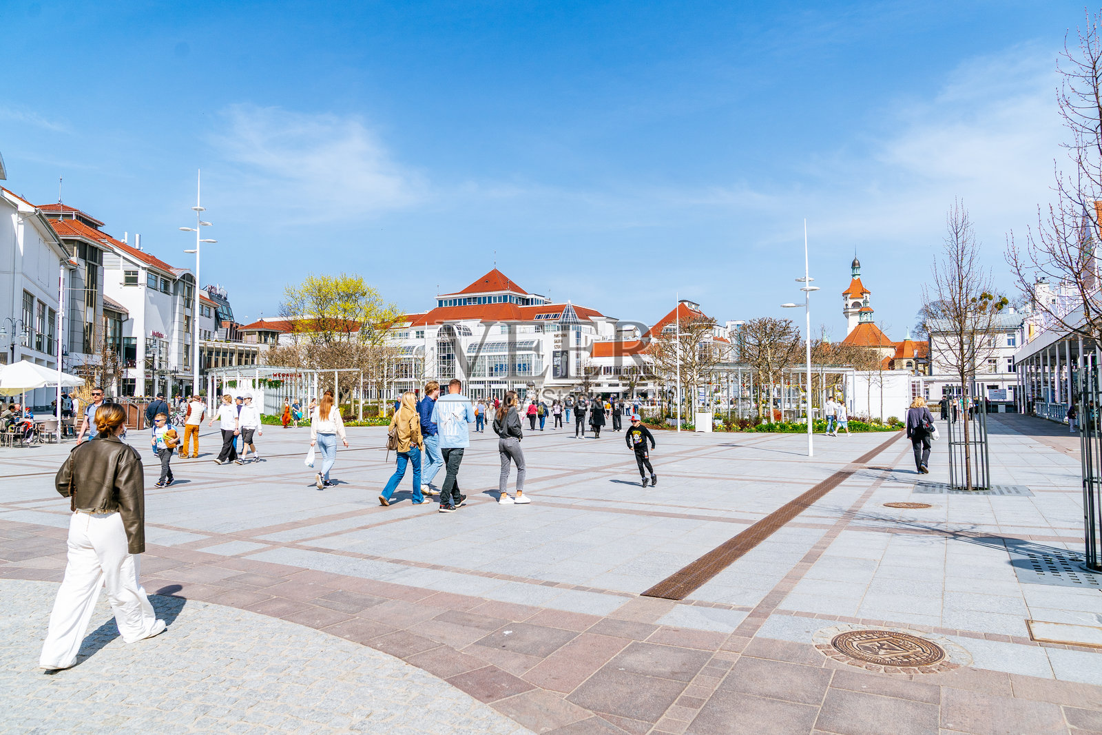 从索波特友谊广场俯瞰水疗中心和灯塔,周围是现代与历史建筑,人们在开放空间中散步和交谈。照片摄影图片