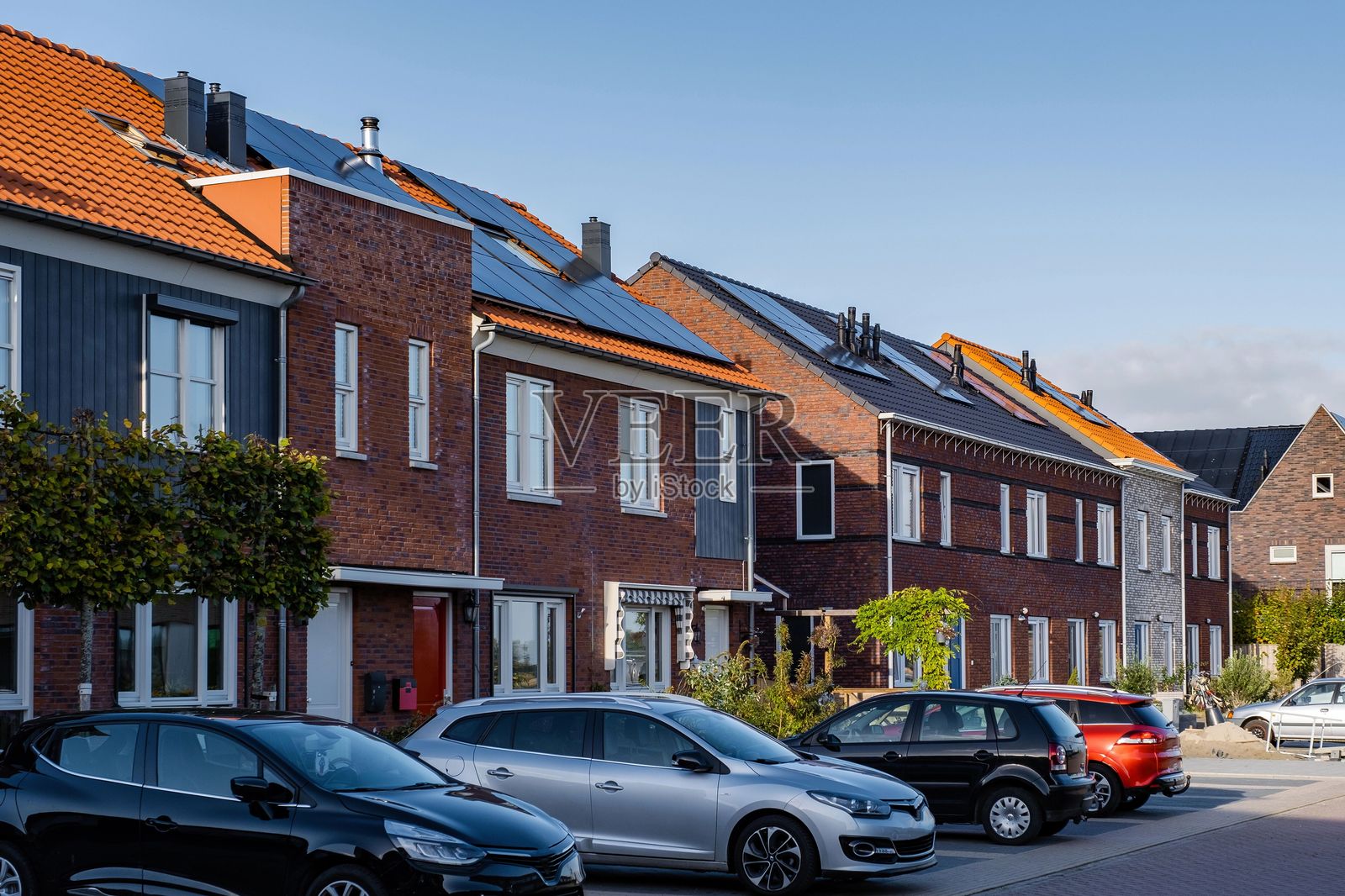 阳光明媚的日子里，街道两旁是现代节能住宅和太阳能电池板。照片摄影图片
