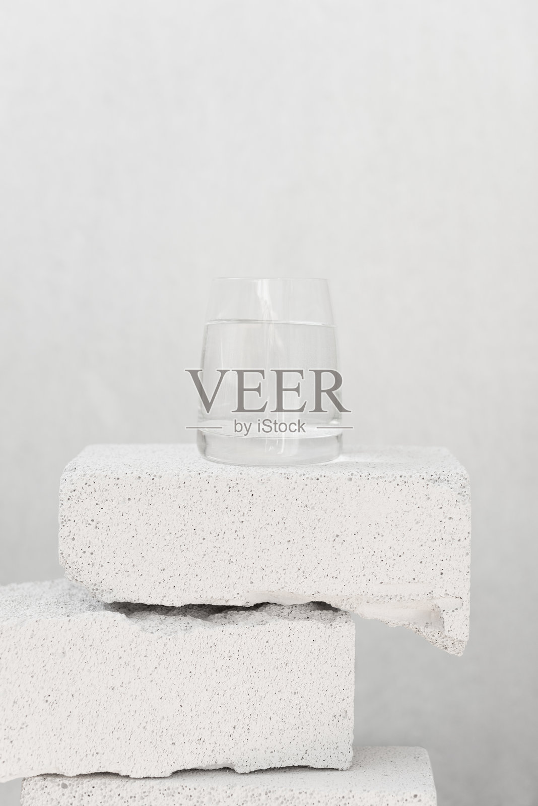 在中性背景上用石块和玻璃平衡构图，搭配纯净水。照片摄影图片